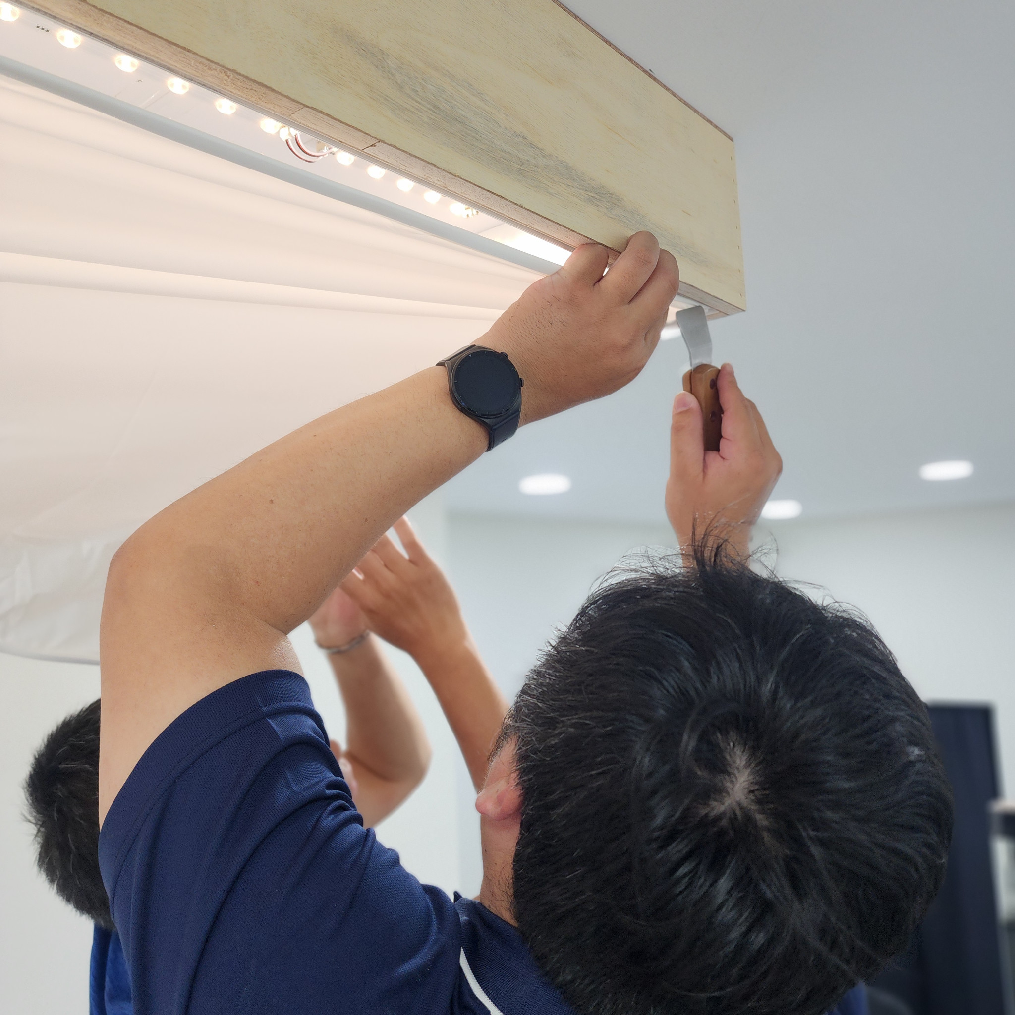 施工人員在光膜邊角使用工具仔細收邊